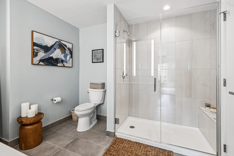 A bathroom with a toilet, a towel, and a painting on the wall.