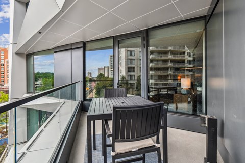 A balcony with a table and chairs overlooks a cityscape.