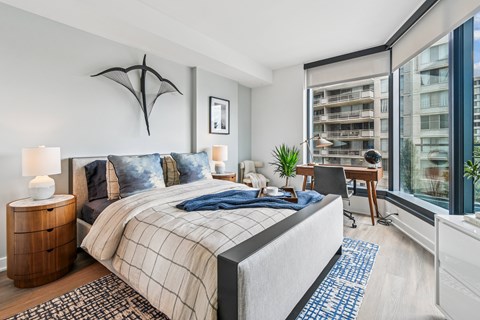 A bedroom with a large bed and a desk with a chair.