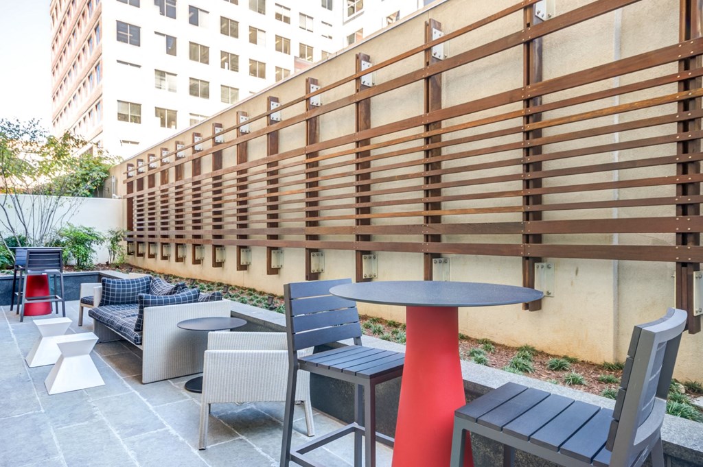 a patio with tables and chairs on the side of a building