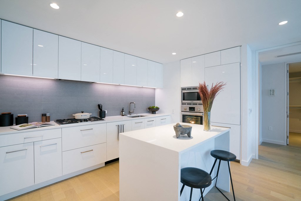 a kitchen with white cabinetry and a white island with two black stools