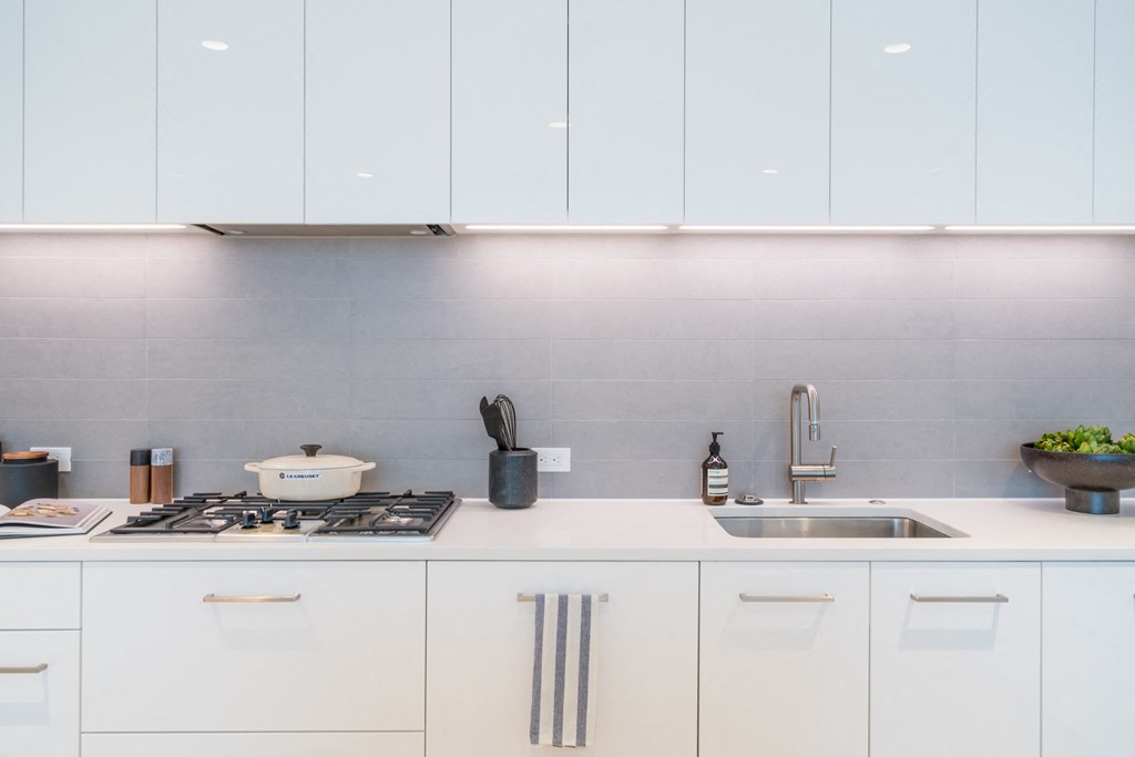 a white kitchen with white cabinets and a stove and sink