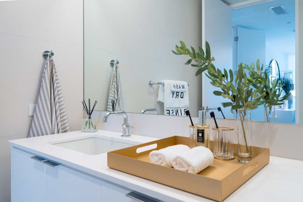 a white bathroom with a sink and a tray with towels on it