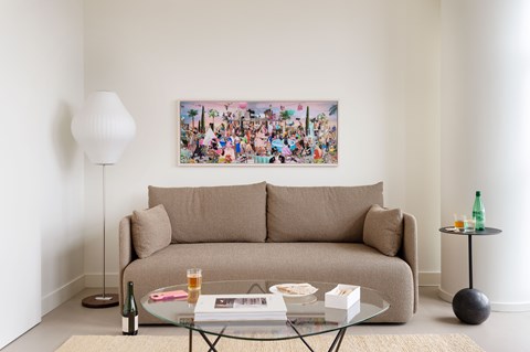 A living room with a couch, a table, a lamp, and a painting on the wall.