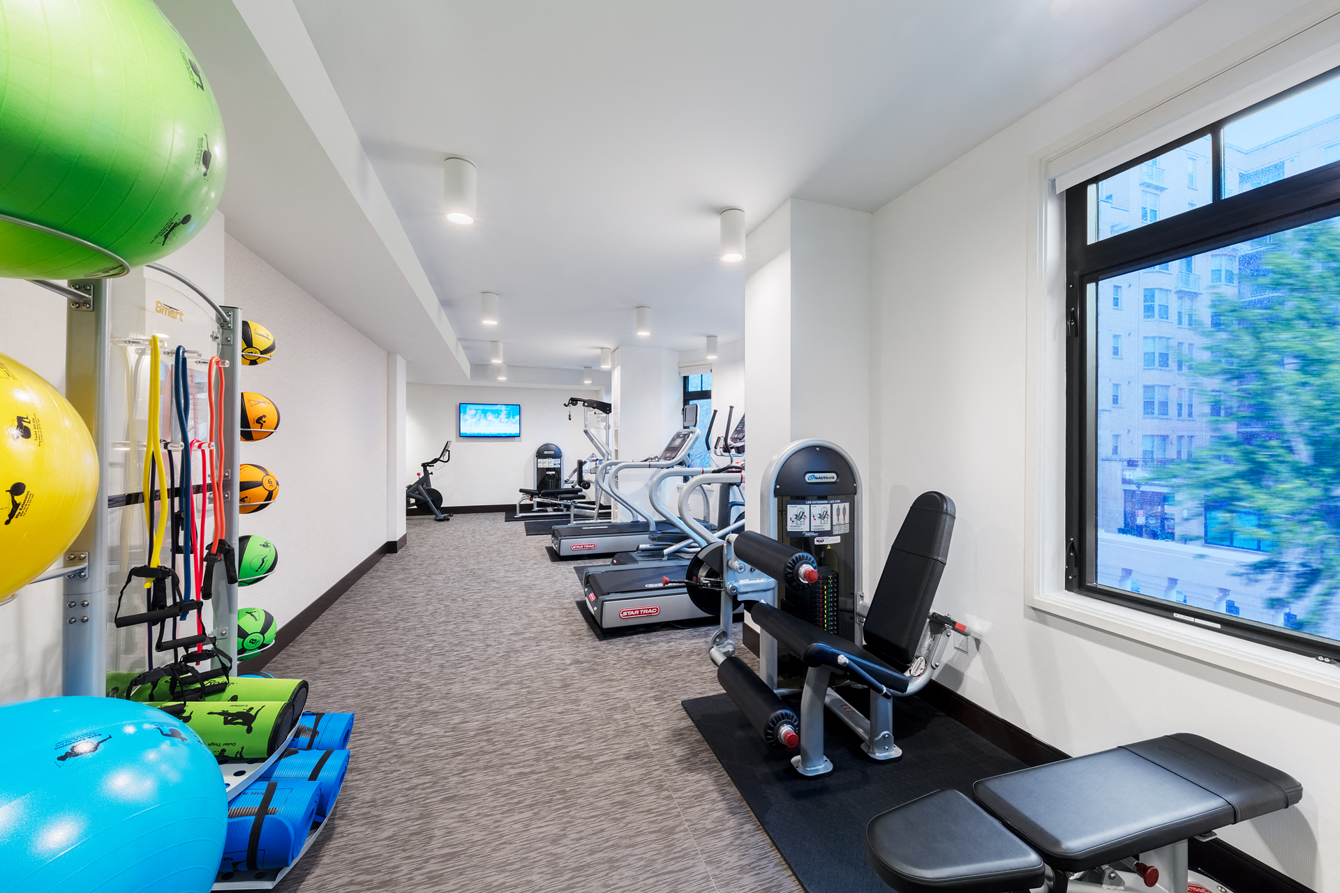 a workout room with weights and other exercise equipment in a building with a large window