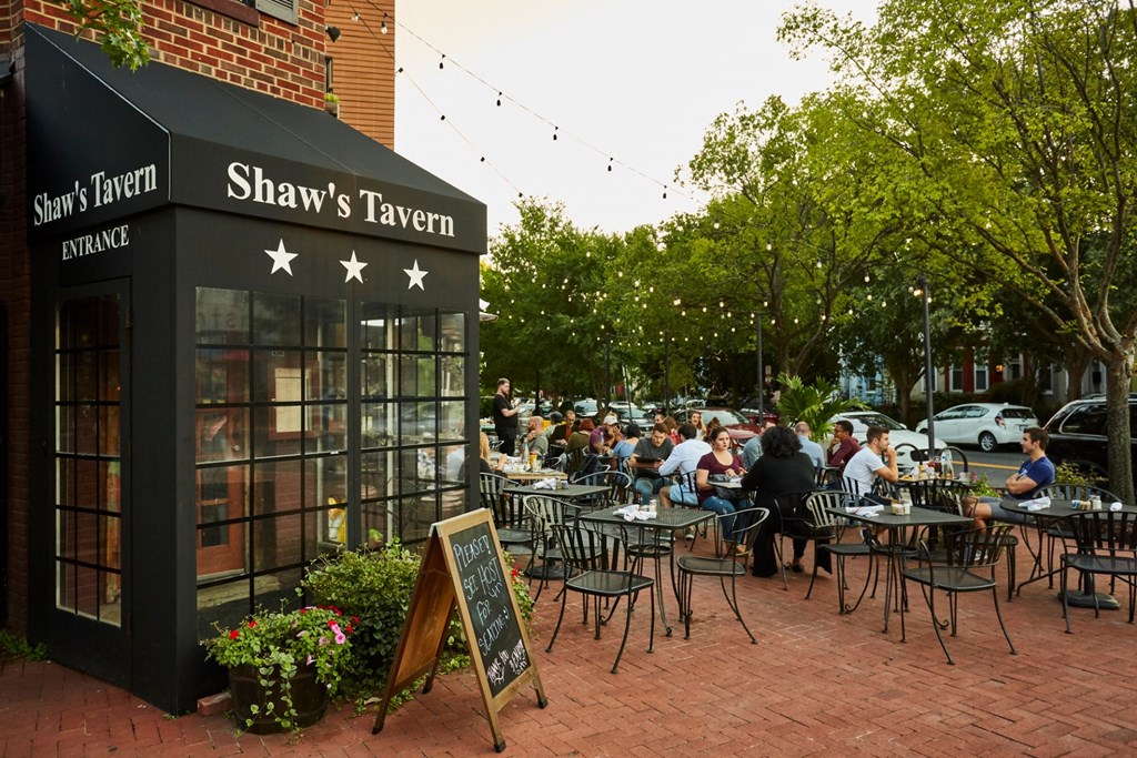 people sitting at tables outside of a restaurant