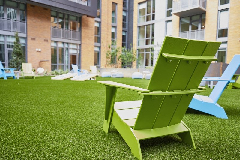 a green lounge chair on the lawn of an apartment building