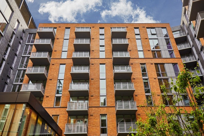 a large brick apartment building with many windows and a blue sky
