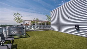 the patio on the top of the building has a lawn and chairs
