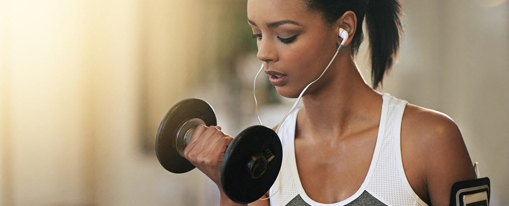 a woman exercising with a dumbbell and headphones