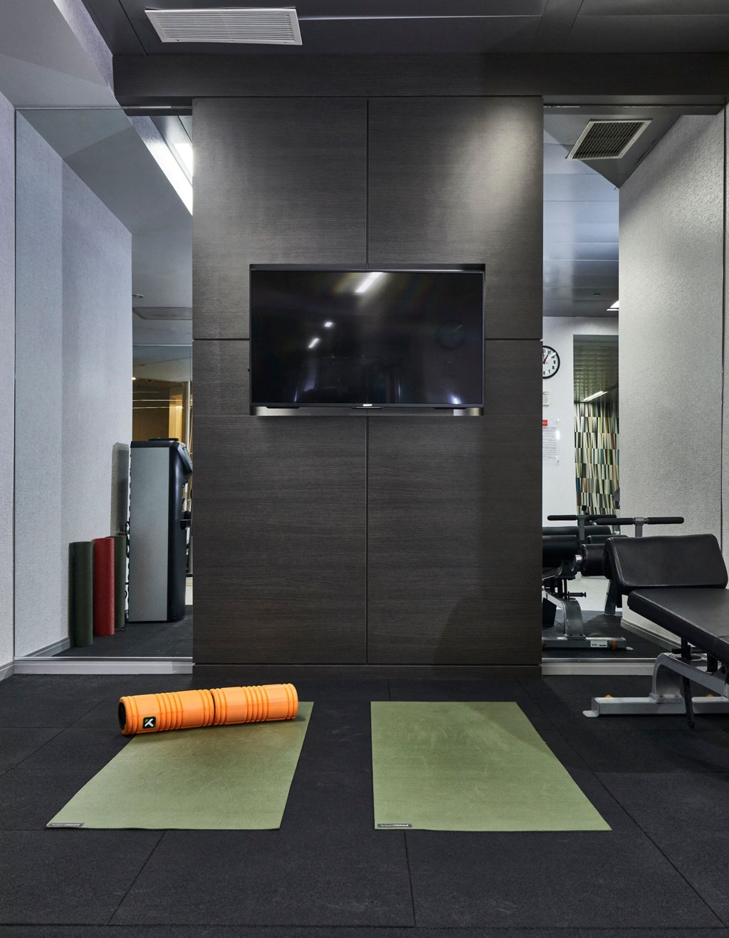 a gym with a television on the wall and weights on the floor