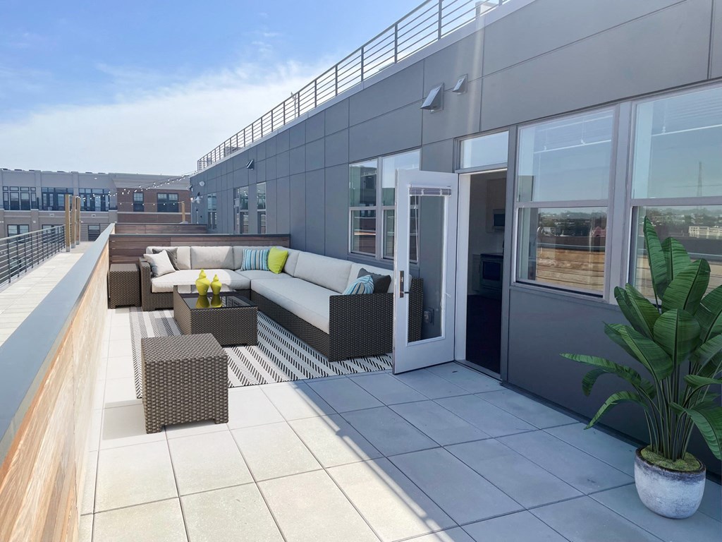 a rooftop terrace with couches and tables on a building