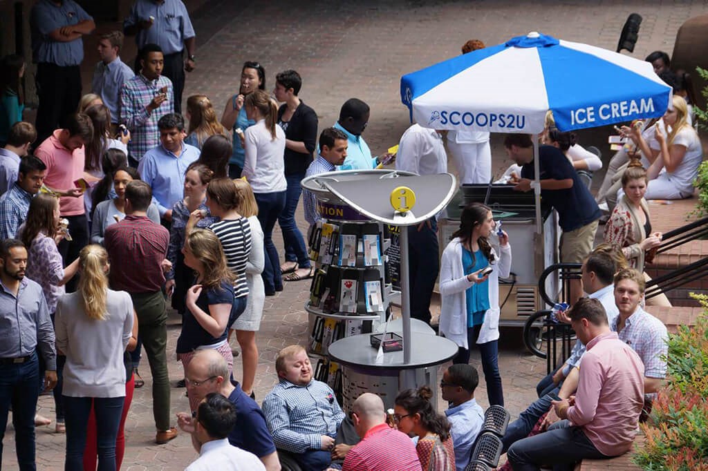 a crowd of people standing around an ice cream stand