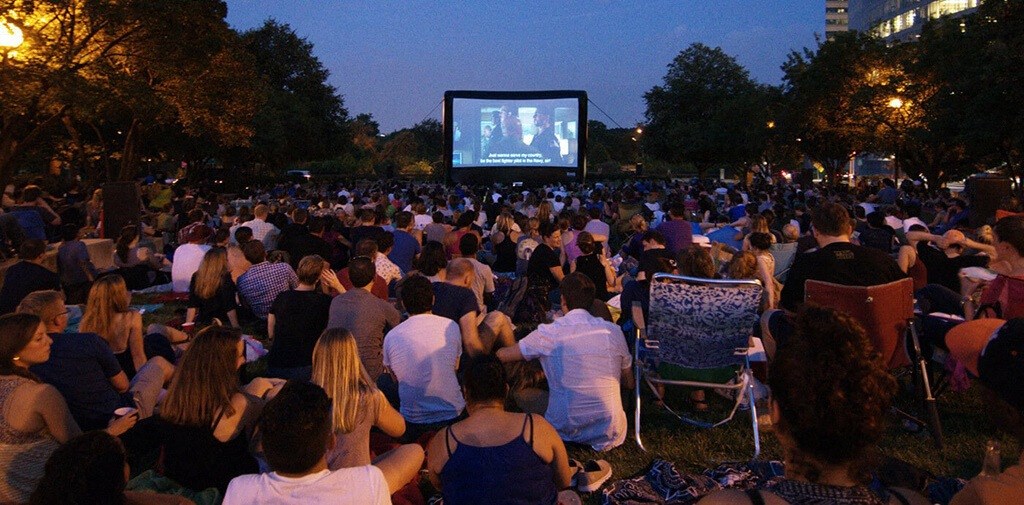 people watching a movie in a park at night