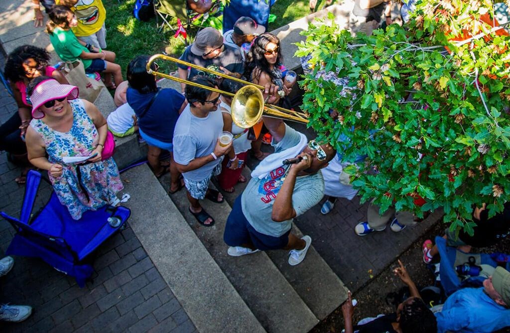a group of people standing around a marching band with a trombone
