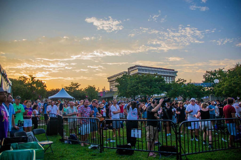 a crowd of people watching a sunset at a music festival