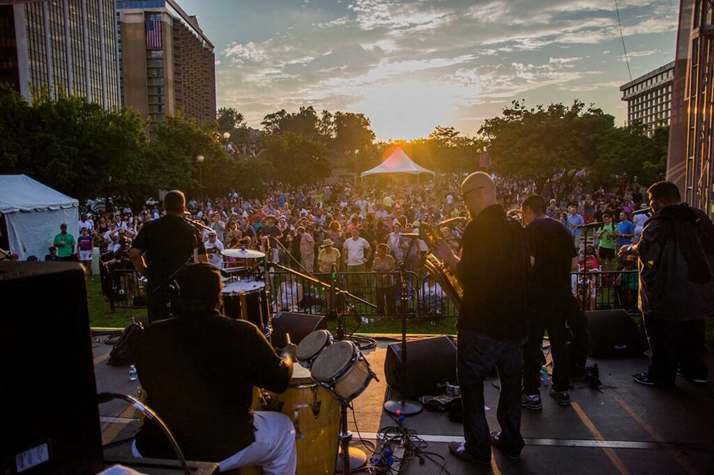 the sun sets over the crowd of people at a concert
