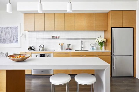 A modern kitchen with a white table and two white stools.