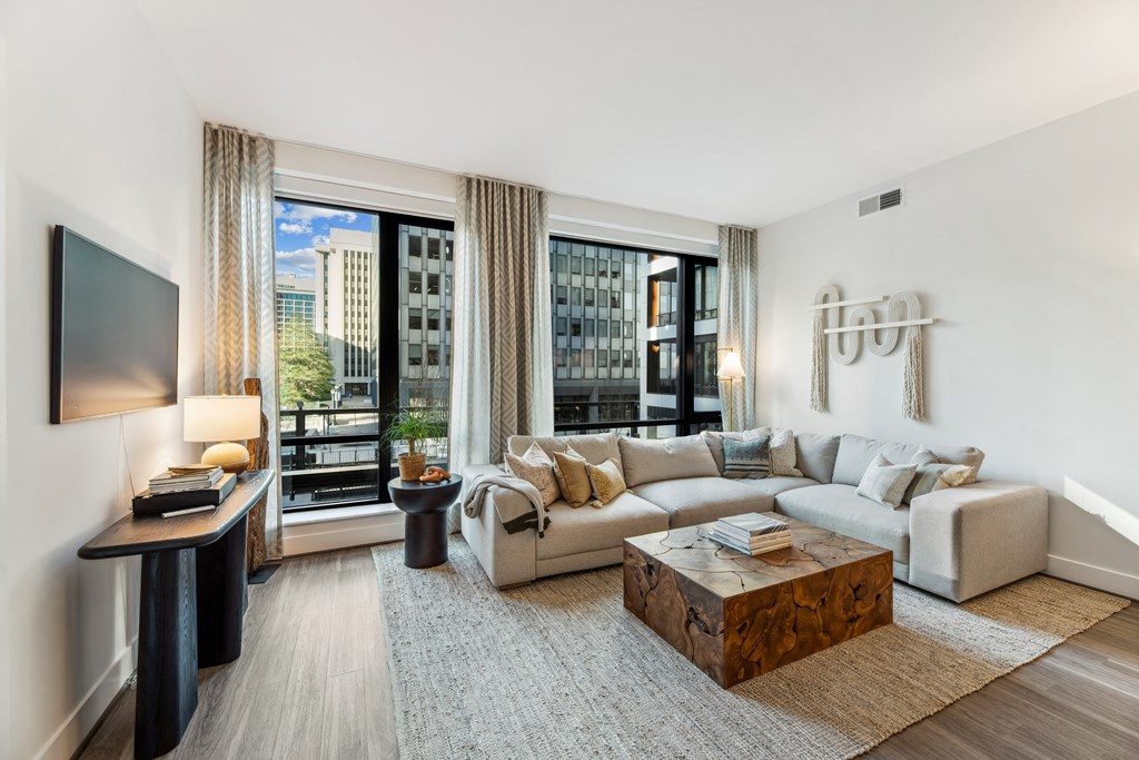 a living room with a couch and a coffee table and large windows