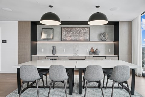 A modern dining room with a large table and grey chairs.