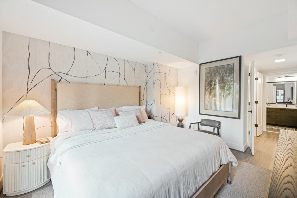 a white bedroom with a large bed and a large painting on the wall