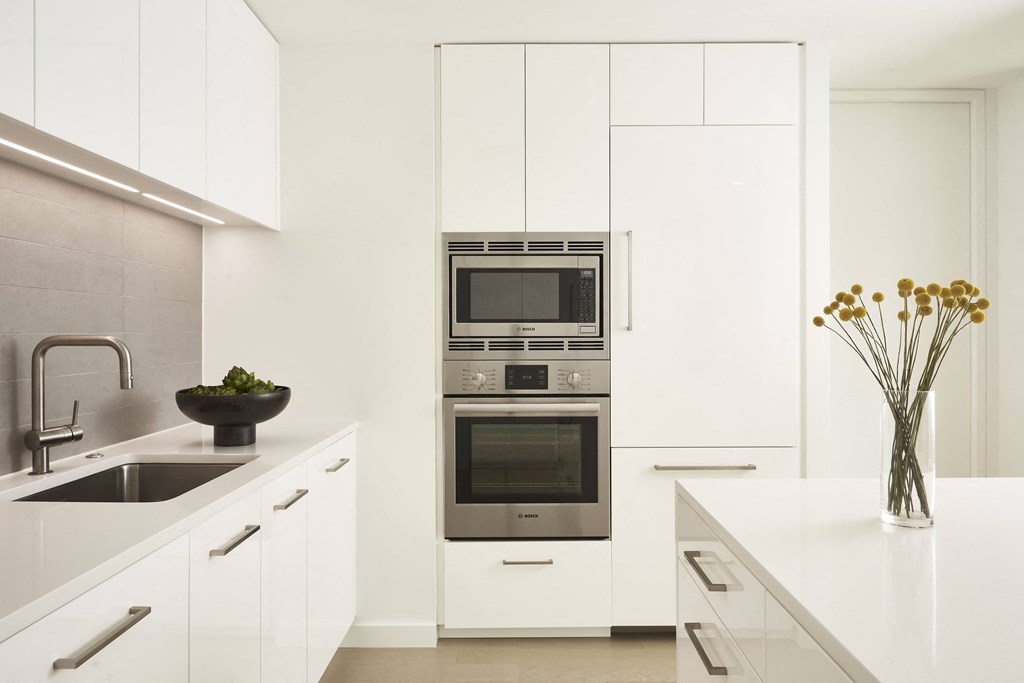 a white kitchen with stainless steel appliances and white cabinets