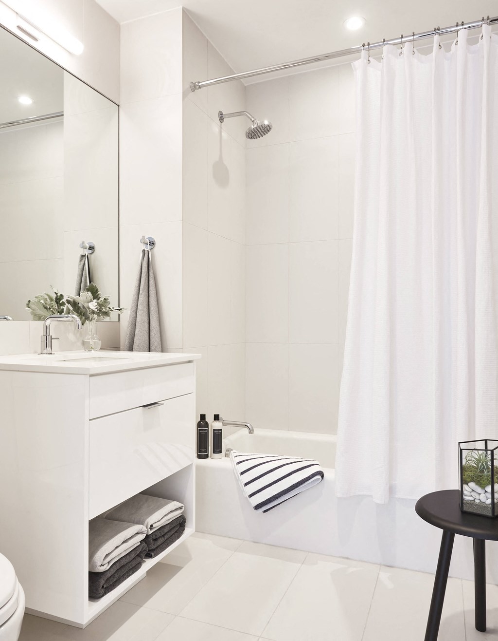 a white bathroom with a shower and a sink and a mirror