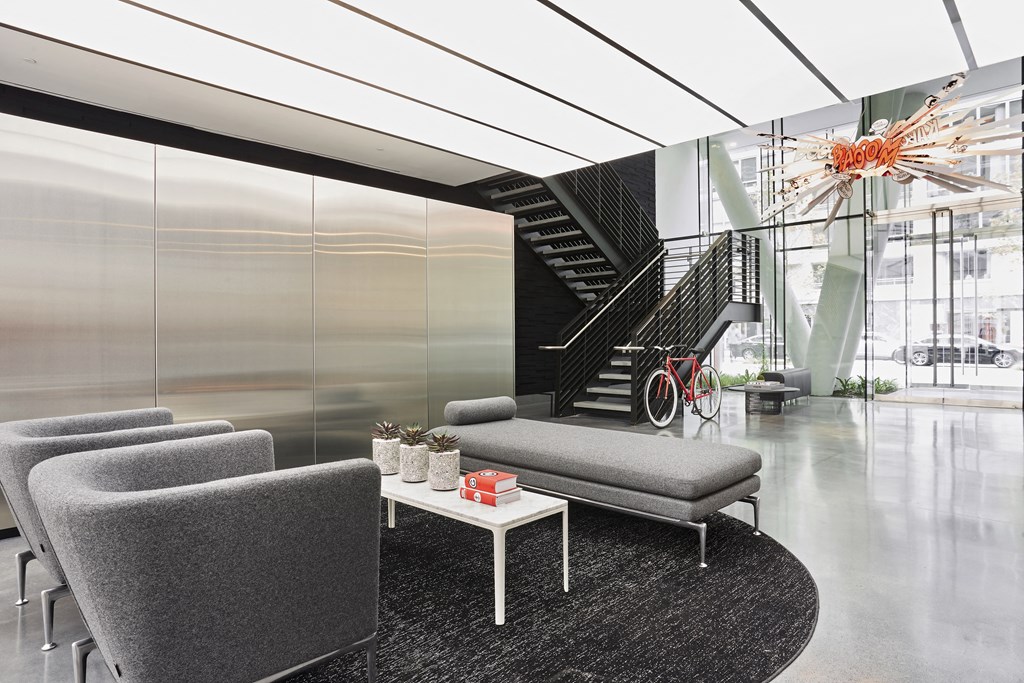 a lobby with chairs and a table and a staircase