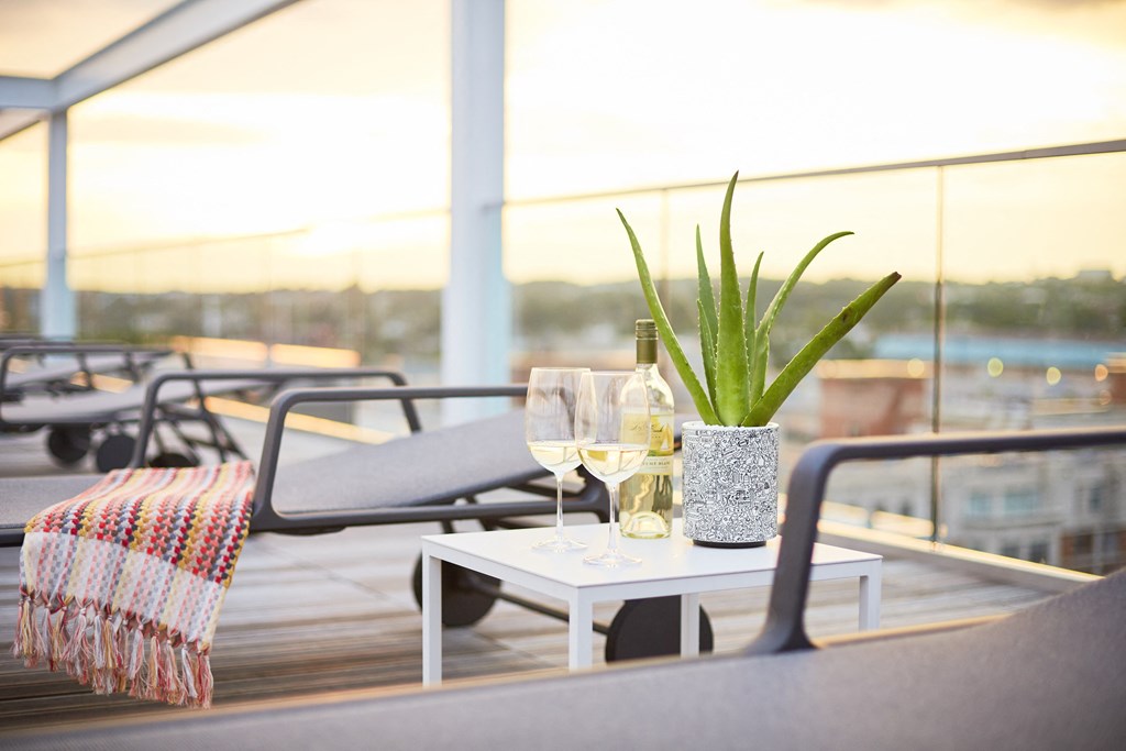 a table with wine glasses and a plant on a balcony