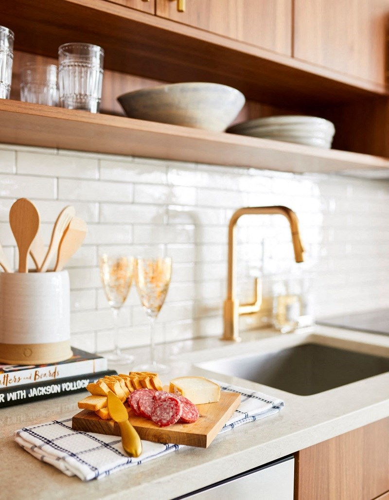 a kitchen sink with a cutting board with meat and cheese on it