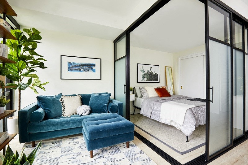 a bedroom with a couch and a bed in a room with glass doors