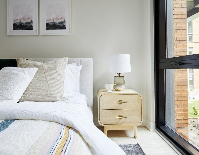 a bedroom with a bed and a nightstand and a window