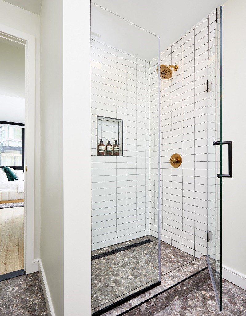 a shower with white tiles and a glass door
