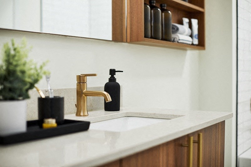a kitchen sink with a gold faucet and a soap dispenser