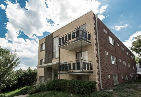 A modern brick building with balconies overlooking a green landscape.