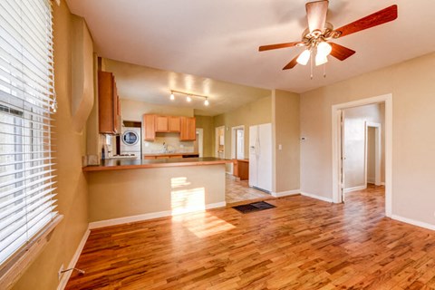 an empty living room and kitchen with a ceiling fan