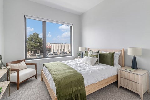 A bedroom with a large bed and a chair by the window.