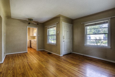 the living room of an empty house with wooden floors and a ceiling fan