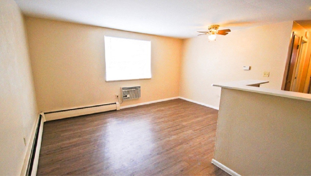 an empty living room with wood floors and a ceiling fan