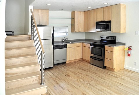 A kitchen with wooden cabinets and a staircase.