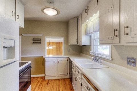 a kitchen with white cabinets and a sink and a window
