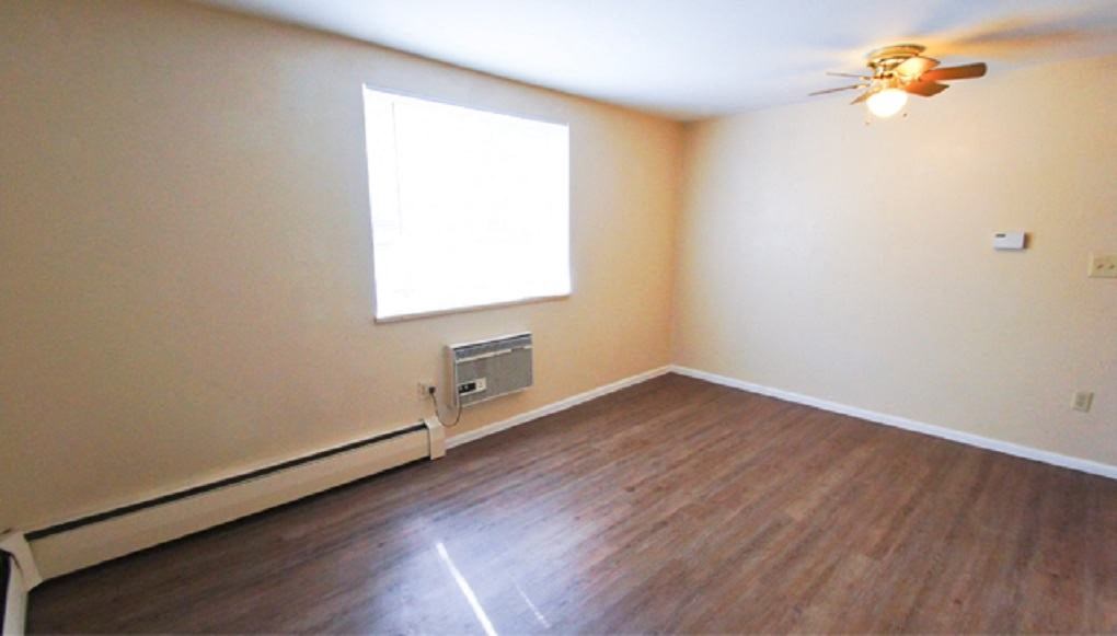 an empty room with a wood floor and white walls