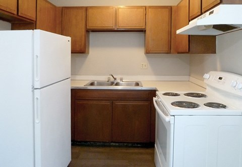 A white refrigerator stands next to a white stove in a kitchen.