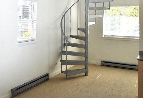 A spiral staircase in a room with a window.