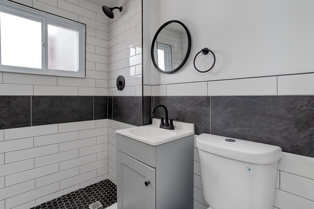 a white bathroom with black and white tiling and a white toilet and sink