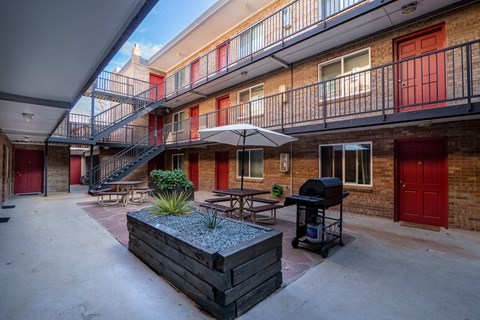 A patio area with a table, chairs, and a grill.