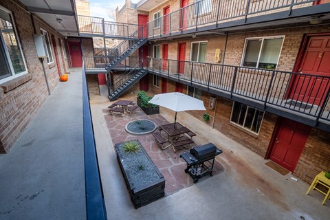 A patio with a table and chairs and an umbrella.