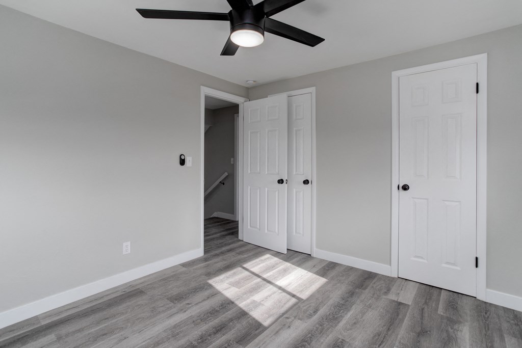 a bedroom with two doors and a ceiling fan