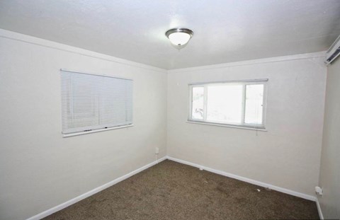 A room with a window and a carpeted floor.