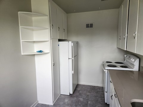 A small kitchen with a white fridge, white stove, and white cabinets.